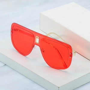Lunettes de soleil bouclier oversize avec verres rouges et branches dorées sur marbre