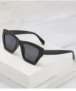 Detail of square black sunglasses with dark gray lenses on white marble background