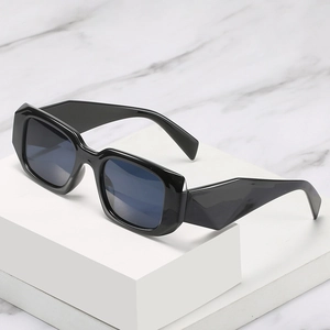 Modern black rectangle sunglasses with thick frames and dark lenses on a white block