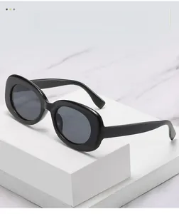 Detail of oval black thick frame sunglasses resting on a white geometric block