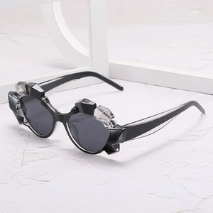Chic polygonal cat eye sunglasses with thick frames and black lenses on white stone