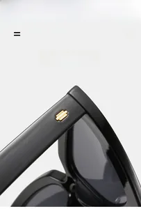 Macro detail of black sunglasses with gold stepped metal logo on the temple hinge