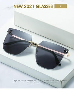 Détail de lunettes de soleil carrées sans monture avec branches dorées et verres de sécurité