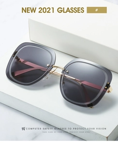 Detail of square oversized sunglasses with grey frame and gold metal bridge on marble