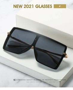 Macro detail of oversized square sunglasses with gold metal hinges on marble surface