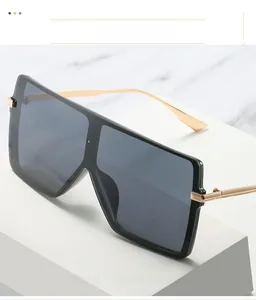 Detail of square oversized sunglasses with black glossy frame and slim gold metal temples