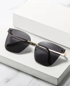 Detail view of rimless geometric sunglasses with gold metal frame on marble surface