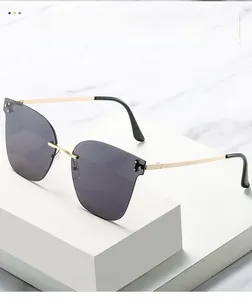 Detail of rimless sunglasses with grey lenses and gold metal temples on a marble stand
