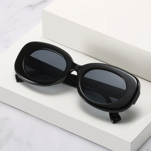 Classic minimalist black oval sunglasses with thick frames on white geometric display stand