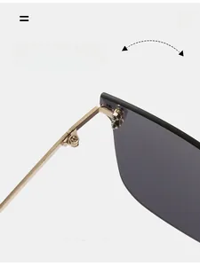 Detail of durable gold metal hinge connecting dark grey lenses on rimless sunglasses