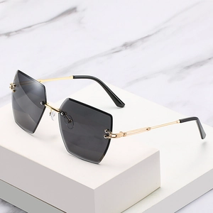 Fashionable rimless geometric sunglasses with grey lenses and gold metal frames on marble