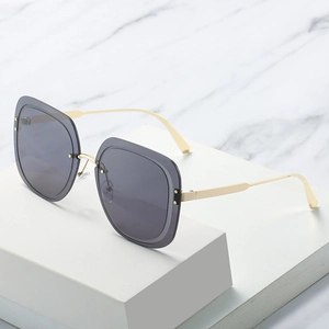 Oversized square sunglasses with gold metal frame and rivet detail on white marble