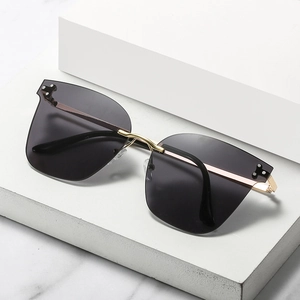 Chic rimless oversized sunglasses with grey lenses and gold metal bridge on stone decor