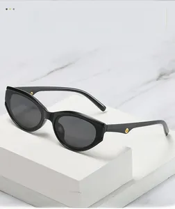 Detail of black cat-eye sunglasses with gold metal hinge accents on marble background