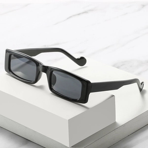 Schicke schwarze rechteckige Sonnenbrille mit herzförmigen Bügelenden auf weißem Podest