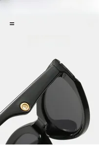 Detail of black frame sunglasses showing gold metal hinge and lightweight texture