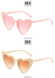 Detail view of pink and beige heart shaped sunglasses with gradient lenses at 45 degree angle
