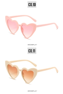Detail view of heart-shaped sunglasses in pink and beige frames with gradient lenses