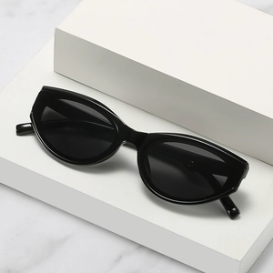 Classic black cat eye sunglasses with glossy finish on a minimalist stone background