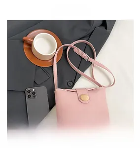 Detail view of pink soft leather crossbody bag with wooden buckle and flat lay styling