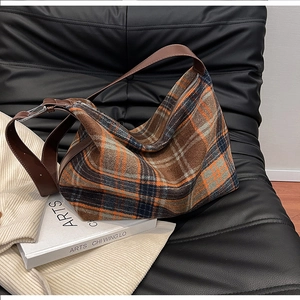 Detail view of the orange-brown plaid tweed hobo bag with a leather adjustable strap