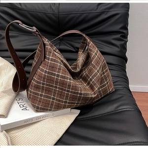 Detail of brown plaid crossbody bag with leather strap and silver metal hardware accents