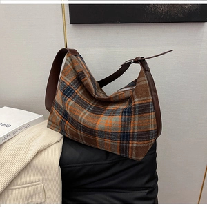 Detailed view of a vintage plaid hobo bag with a leather strap in a minimalist setting