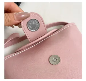 Close-up of magnetic buckle closure on pink soft leather bag with fine white stitching