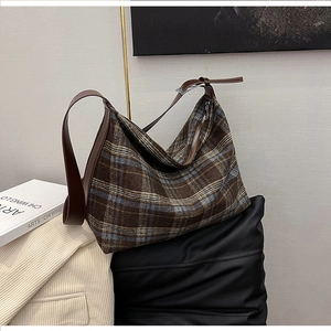 Detail of hobo bag with vintage plaid pattern, brown leather trim and metal zipper