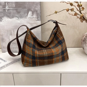 Close-up of vintage orange and blue plaid wool underarm bag with dark brown leather strap