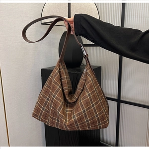Detail of checkered hobo bag with brown leather strap and silver metal adjustment buckle