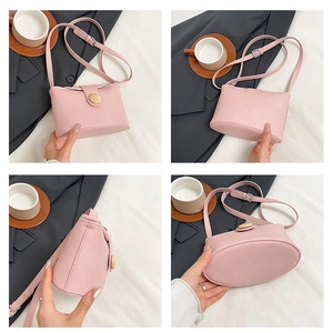 Detail view of pink soft leather bag with wood button accent and adjustable strap
