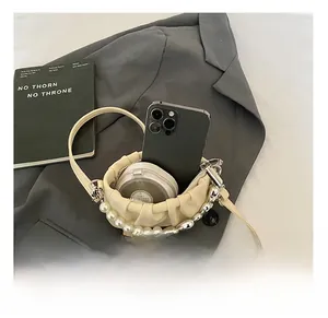 Internal capacity of pleated beige mini bag showing smartphone and makeup items