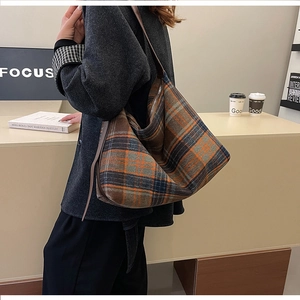 Side view of large plaid tote bag with brown leather strap for autumn fashion