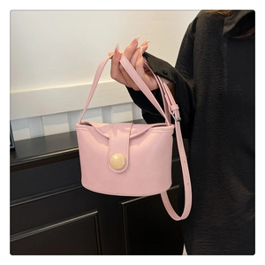 Detail of pink soft leather small bucket bag with round button held by hand