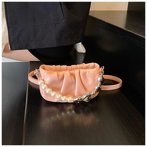 Detail of pink pleated mini bag featuring pearl and silver heart chain on black stairs