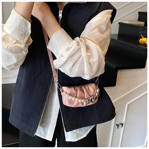 Detail of pink pleated mini bag featuring white pearls and silver heart-shaped charms