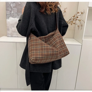 Close-up of brown plaid crossbody bag in textured tweed worn with a dark grey coat