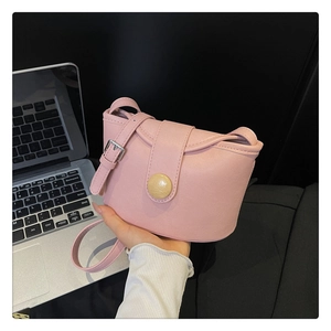 Detailed close-up of pink leather bucket bag with round buckle and adjustable strap