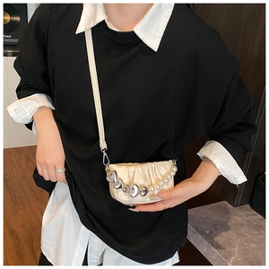 Detail of cream pleated mini bag featuring silver heart charms and pearl decorative chain