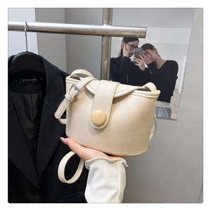 Detailed close-up of beige faux leather square bag featuring a marbled round button detail