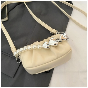 Detail of cream pleated crossbody bag with pearl handle and silver heart accents