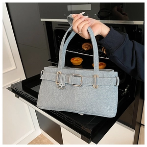 Close-up of light blue denim textured shoulder bag with vintage silver buckle and belt straps
