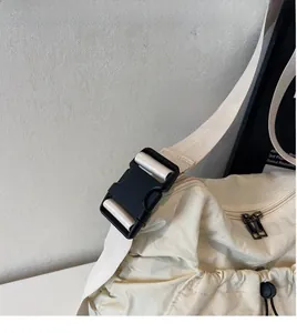 Detail of adjustable black buckle and wide nylon shoulder strap on off-white crossbody bag