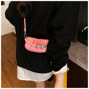 Detailed close-up of pink pleated cloud bag featuring pearl and heart charm chain straps