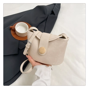 Detail of beige faux leather bucket bag with wooden button and silver strap buckle