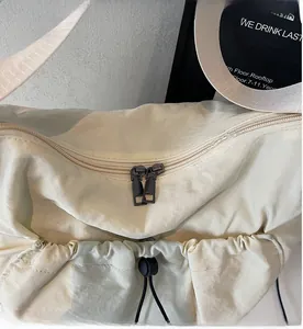 Detail of smooth double metal zippers and drawstring on cream canvas shoulder bag
