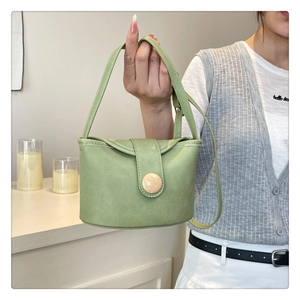 Detail of green soft leather bucket bag with large round buckle and matching strap