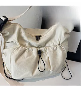 Detail of off-white canvas crossbody bag showing drawstring pocket and wide strap
