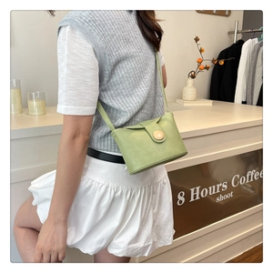 Detail of avocado green leather crossbody bag with decorative round wood grain button